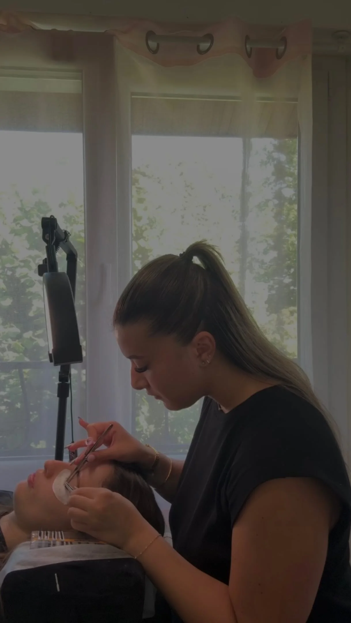 Ambre réalise une pose d'extension de cils en cabine.